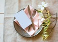 Spring Table Place Setting with white flowers, pink napkin, silverware and a blank card for party menu or invitation. Royalty Free Stock Photo