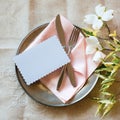 Spring Table Place Setting with white flowers, pink napkin, silverware and a blank card for party menu or invitation.