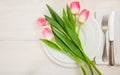 Spring table setting with pink tulips on white wooden background. Top view, copy space Royalty Free Stock Photo