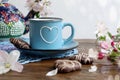 Spring tea party: a cup of tea with a drawn heart, heart-shaped cookies, apple tree branches, against the background of a multi-