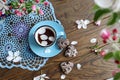 Spring tea party: cup of tea, heart shaped cookies, apple tree branches on blue lace napkin, top view