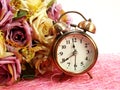 Spring time with alarm clock and artificial flowers bouquet background Royalty Free Stock Photo