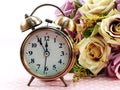 Spring time with alarm clock and artificial flowers bouquet background Royalty Free Stock Photo