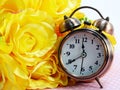 Spring time with alarm clock and artificial flowers bouquet background Royalty Free Stock Photo