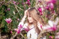 Spring time. Cute girl happy smiling on spring landscape near magnolia blossom. Adorable girl smile in park with blossoming Royalty Free Stock Photo