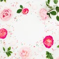 Spring time frame. Floral composition of pastel pink roses flowers and bright confetti on white background. Flat lay, top view Royalty Free Stock Photo