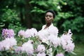 Spring time. Portrait of young afro american woman surrounded purple flowers in park Royalty Free Stock Photo