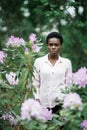 Spring time. Portrait of young afro american woman surrounded purple flowers in park Royalty Free Stock Photo