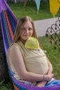 Spring time. a young girl with a baby doll is resting in a hammock