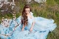 Spring touch. Happy beautiful young smiling woman in blue dress enjoy fresh flowers and sun light in blossom park at Royalty Free Stock Photo