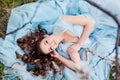 Spring touch. Happy beautiful young smiling woman in blue dress enjoy fresh flowers and sun light in blossom park at