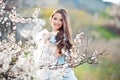 Spring touch. Happy beautiful young smiling woman in blue dress enjoy fresh flowers and sun light in blossom park at Royalty Free Stock Photo