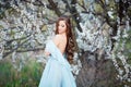 Spring touch. Happy beautiful young woman in blue dress enjoy fresh flowers and sun light in blossom park at sunset Royalty Free Stock Photo