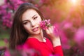 Spring touch. Happy beautiful young woman in red dress enjoy fresh pink flowers and sun light in blossom park at sunset. Royalty Free Stock Photo