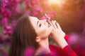 Spring touch. Happy beautiful young woman in red dress enjoy fresh pink flowers and sun light in blossom park at sunset. Royalty Free Stock Photo