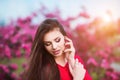 Spring touch. Happy beautiful young woman in red dress enjoy fresh pink flowers and sun light in blossom park at sunset. Royalty Free Stock Photo