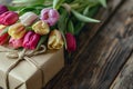 Spring tulips lying on table with wrapped gift box. Royalty Free Stock Photo