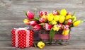 Spring tulips in wooden basket, red polka-dot gift box.