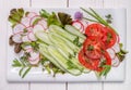 Spring vegan salad with tomato, cucumbers, radish on a white plate. Top view. Royalty Free Stock Photo