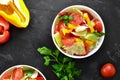 Spring vegetable salad. Salad, tomatoes, cabbage, dressing, bell pepper, cucumber, parsley. Dark background, top view. Healthy