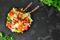 Spring vegetable salad. Salad, tomatoes, cabbage, dressing, bell pepper, cucumber, parsley. Dark background, top view. Healthy