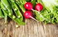 Spring vegetables on wooden background. Radish, green peas and green salad - fresh harvest from the garden. Royalty Free Stock Photo