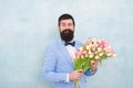 Spring vibes. Man bearded suit bow tie hold tulip flowers bouquet. Gentleman romantic surprise for her. Flowers delivery Royalty Free Stock Photo