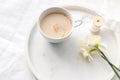 Spring wedding still life composition. Closeup of cup of coffe with milk, silk ribbon, narcissus, daffodil flowers on