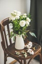 Spring white buttercup flowers in enamel jug on wooden chair Royalty Free Stock Photo