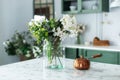 Spring wild flowers in vase and turk with coffee in kitchen table. Bouquet of flowers and plants in glass vase at home.