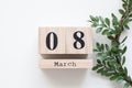 Spring wreath of green leaves with a wooden calendar on white background. Wooden block calendar. Concept International Women`s Day Royalty Free Stock Photo