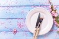 Springr table setting. Pink flowers, knife and fork on white p