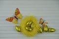 Springtime Easter decoration with yellow nest filled with shiny golden color eggs and butterfly shape decorations Royalty Free Stock Photo