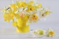 Springtime daffodils in full bloom and Easter eggs on white wooden table