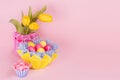 Springtime easter festive background - homemade painted multicolored eggs, tulips bouquet on pastel light pink background.