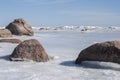 Springtime landscape with closeup of stones in Gulf of Riga covered with ice