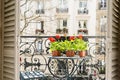 Springtime with red geraniums on a balcony in Paris, France