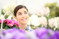 springtime woman smiling in garden and looking up with white wicker basket flowers of purple primroses
