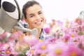 Springtime woman smiling in garden watering daisies flowers