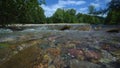 Springwater moves from mountans to river. Spring time. Forest on the background. Many stones. Stormy water flow. Melting