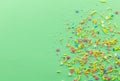 Sprinkle background with multicolored cake topping sprinkles scattered on pale green backdrop with space for text - top view