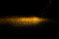Sprinkle glitter gold dust in the dark textured abstract background Royalty Free Stock Photo