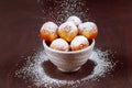 Sprinkle homemade munchkins with sugar powder on blue dish