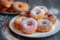 Sprinkled baked donuts on white plate on the table