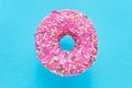 Sprinkled Pink Donut. Glazed sprinkled donut on blue background. Top view, copy space Royalty Free Stock Photo