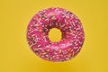 Sprinkled Pink Donut. Glazed sprinkled donut on yellow background. Top view, copy space Royalty Free Stock Photo