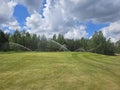 Sprinkler system for watering a golf course on a sunny day Royalty Free Stock Photo
