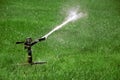 Sprinkler watering field of green grass Royalty Free Stock Photo