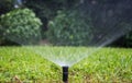 Sprinkler watering the lawn in a park, bokeh background. Royalty Free Stock Photo