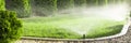 Sprinklers watering grass, green lawn in garden Royalty Free Stock Photo